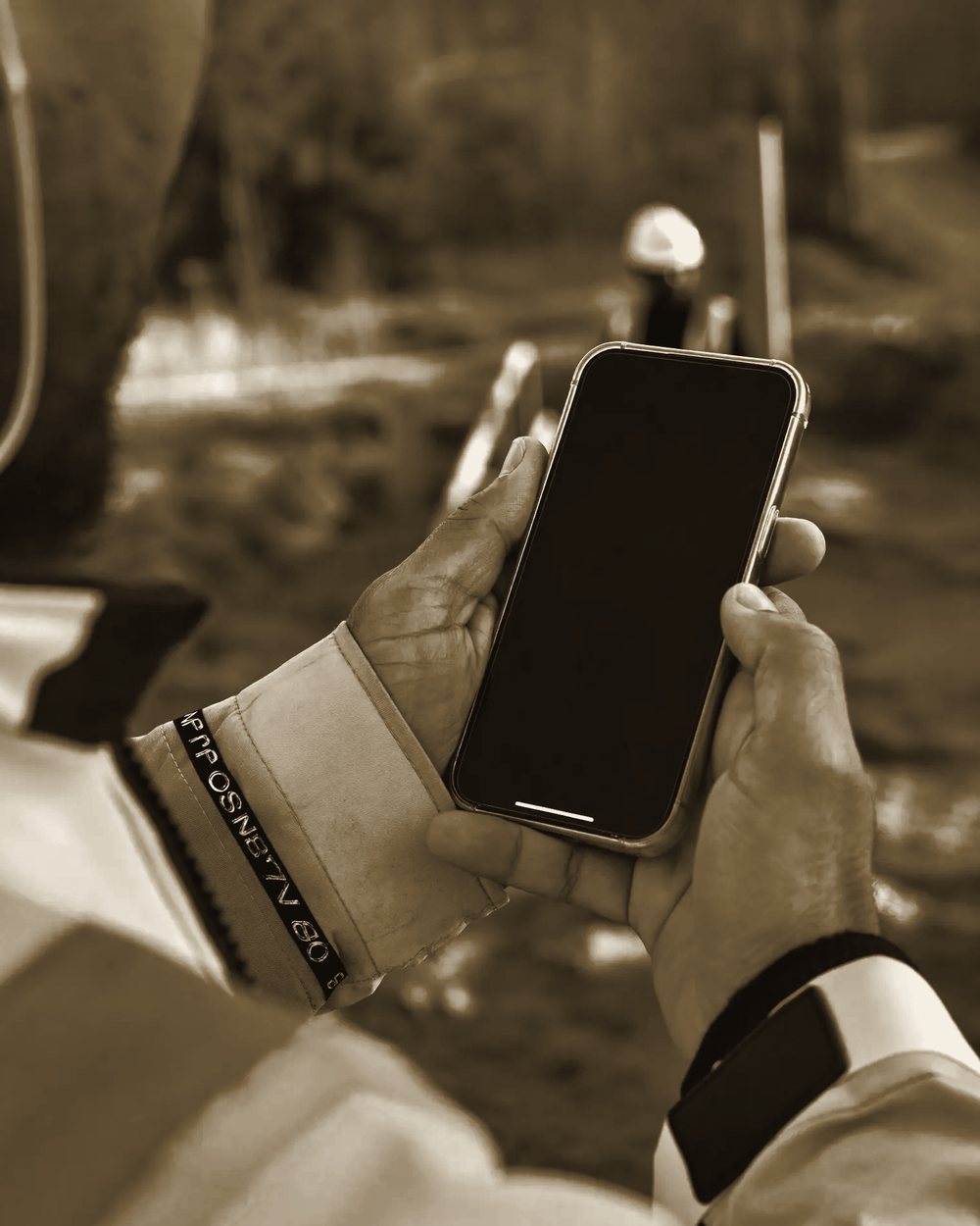 Handwerker in Warnjacke schaut auf der Baustelle aufs Smartphone