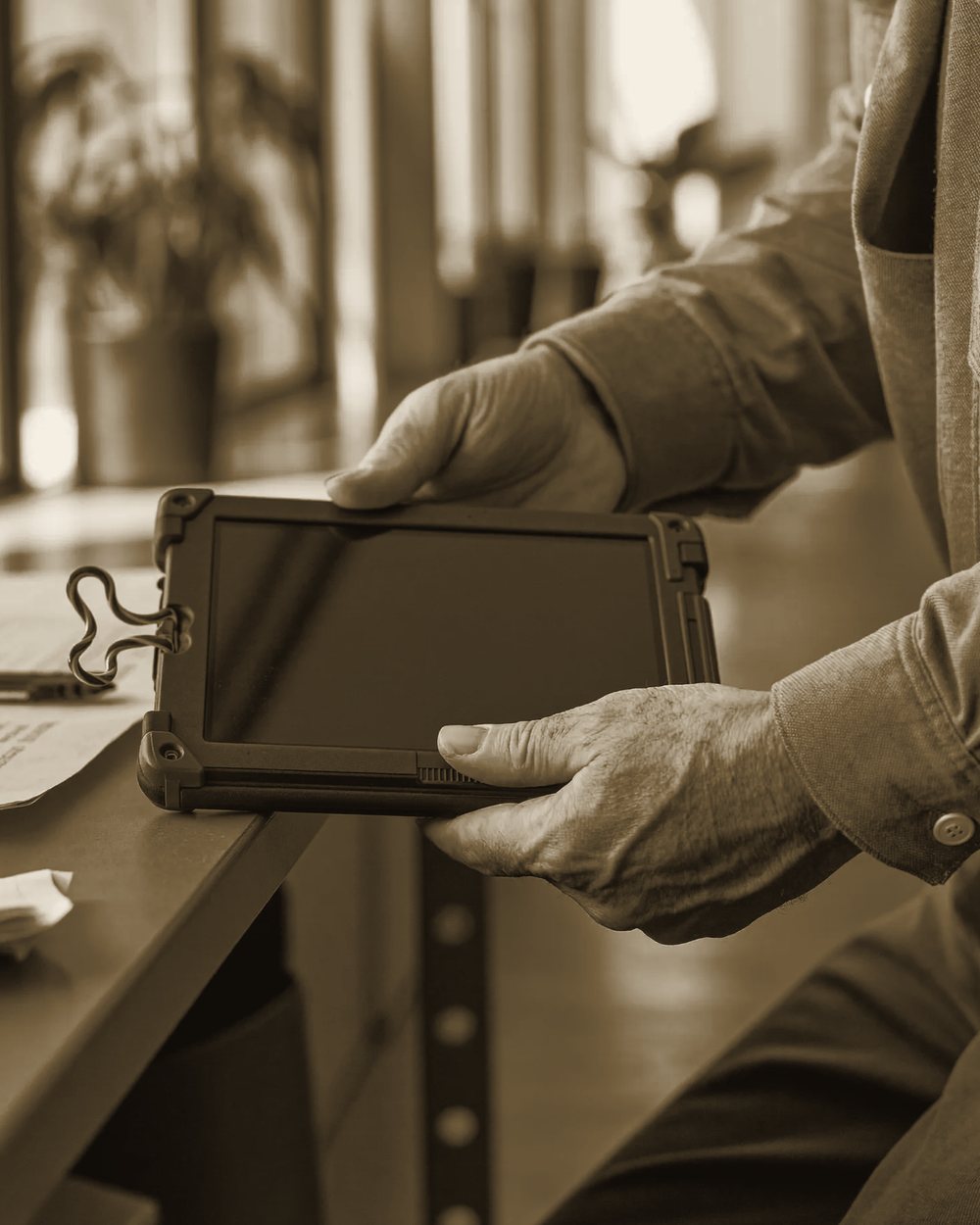 Hände halten ein robustes Tablet, daneben ein beiseitegelegtes Klemmbrett